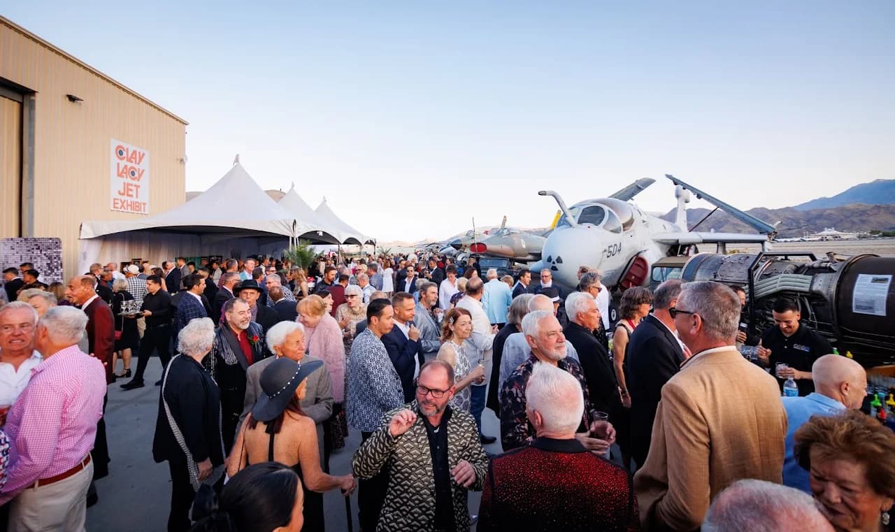 Crowd gathering outdoors beside an aircraft during a formal event