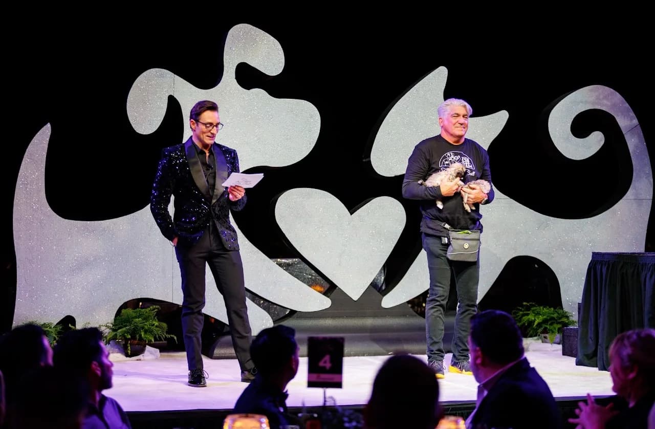 Two presenters speaking on stage before seated guests