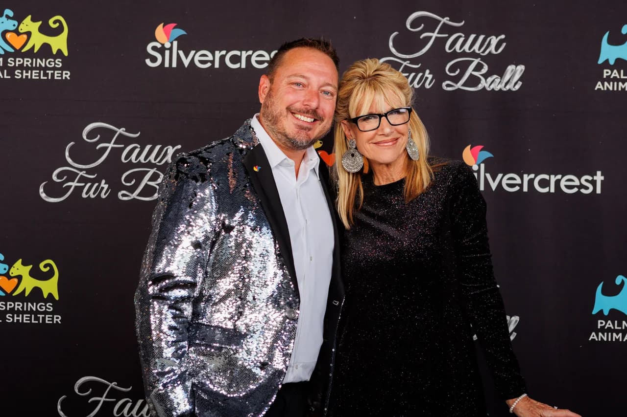 Two guests posing together before a step-and-repeat event backdrop