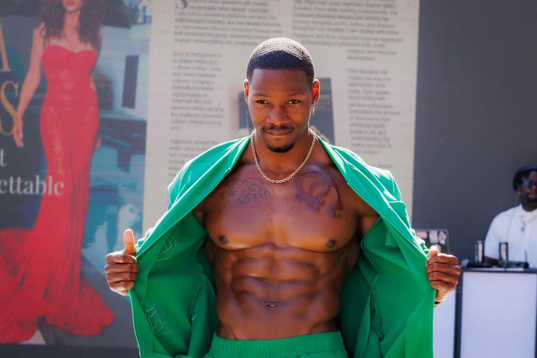 Model holding open a green jacket during an outdoor fashion presentation