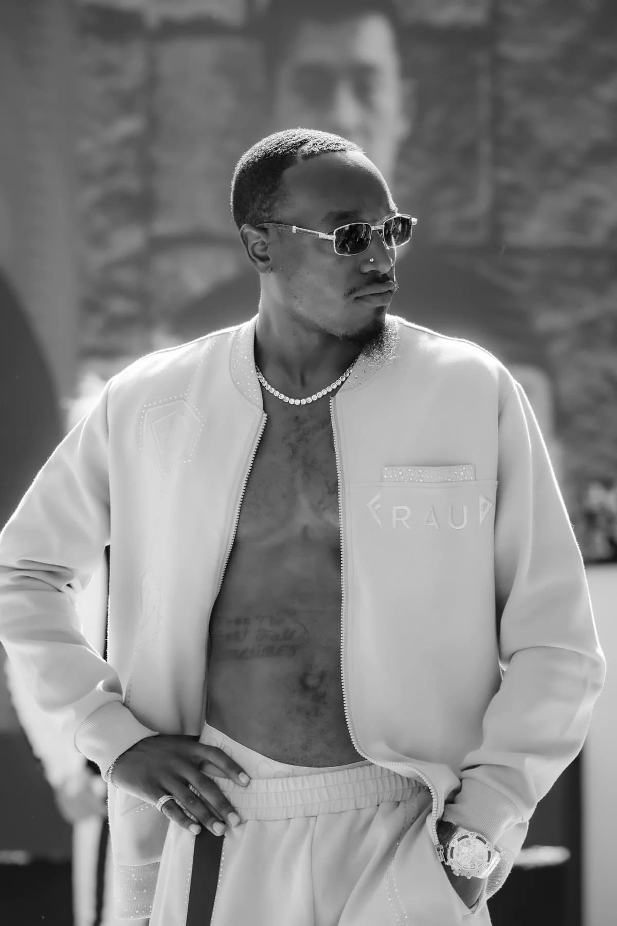 Black-and-white portrait of a model wearing sunglasses and an open light-colored jacket