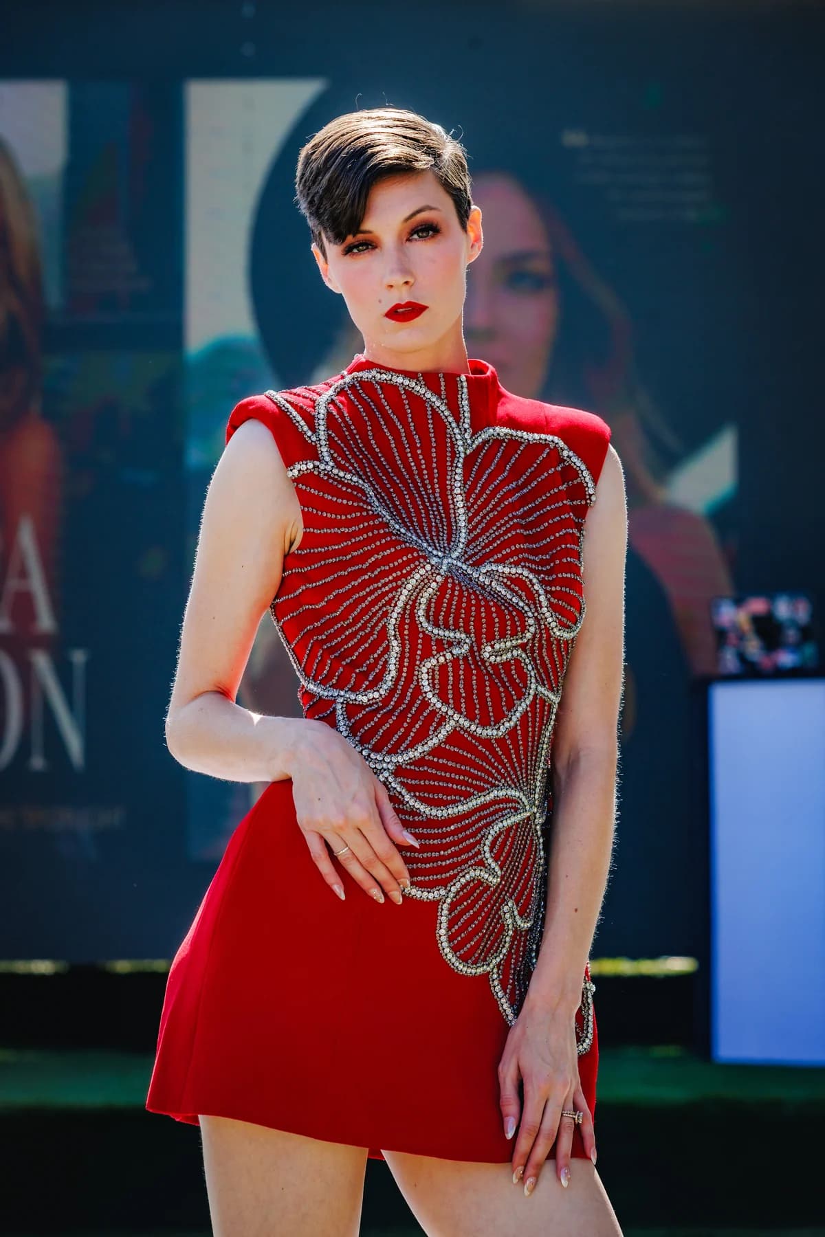 Model wearing a red beaded outfit during an outdoor fashion presentation