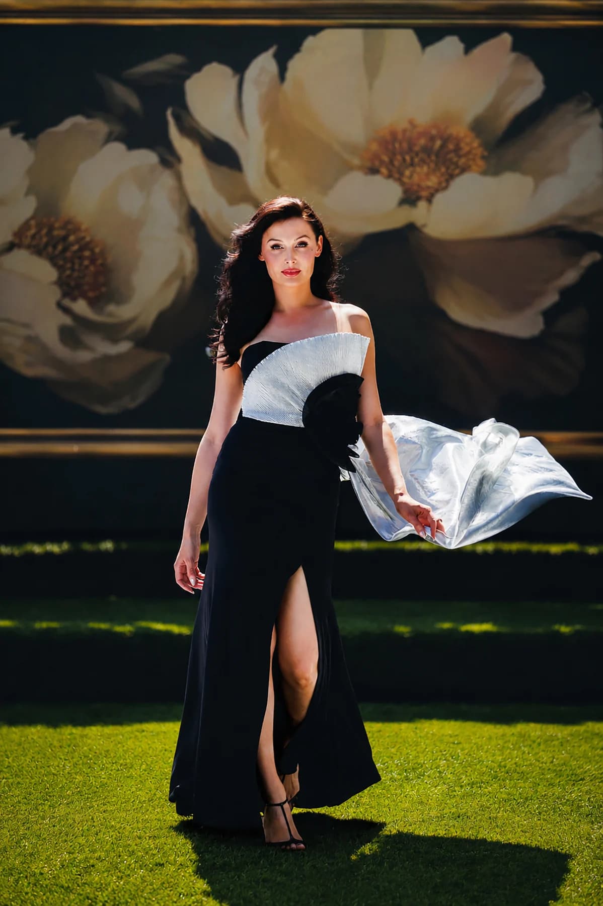 Model presenting a black evening gown with a flowing white sculptural sleeve