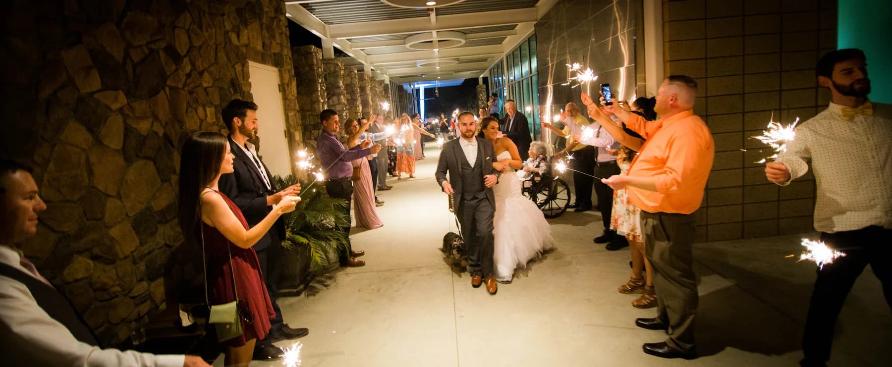 Stephen and Heather moving through a sparkler exit with guests lining the walkway