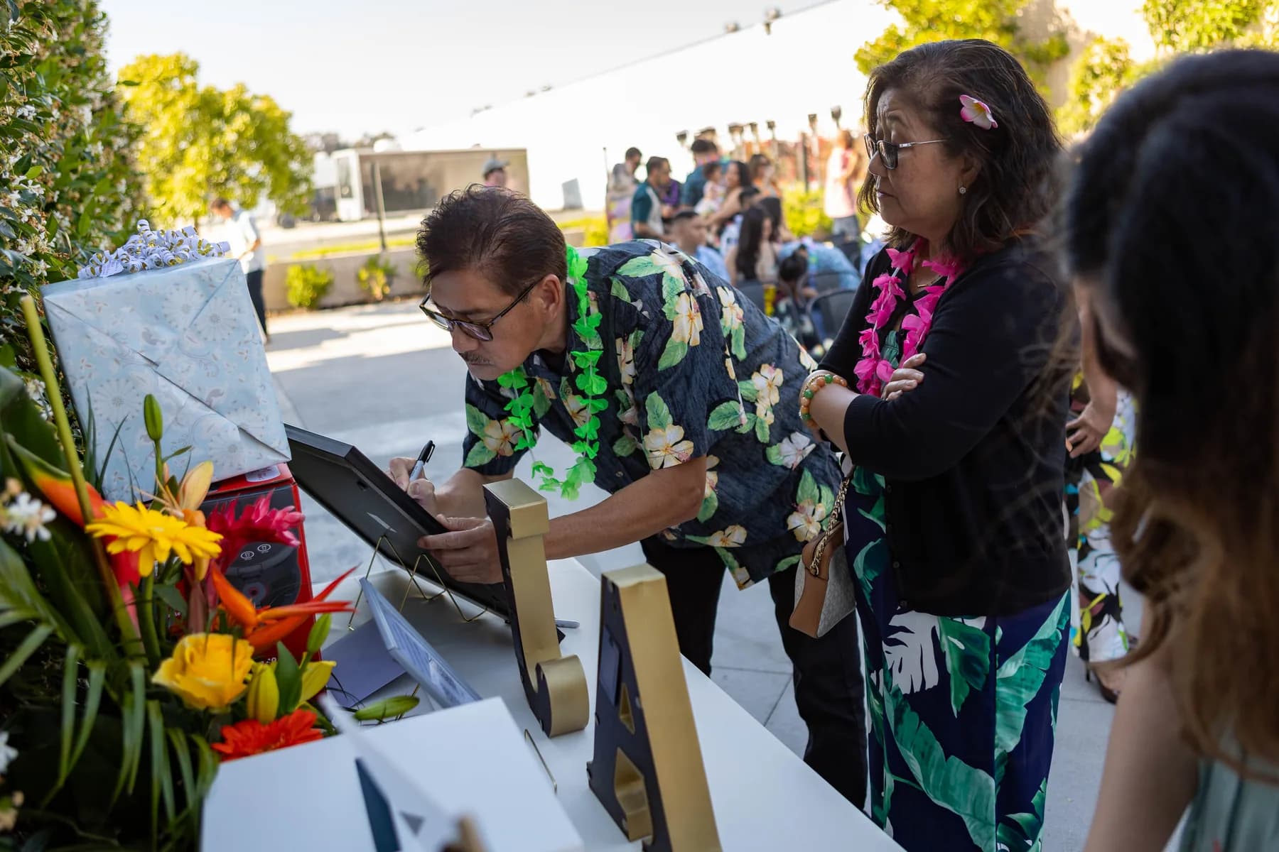 Guests signing in beside tropical flowers before the ceremony