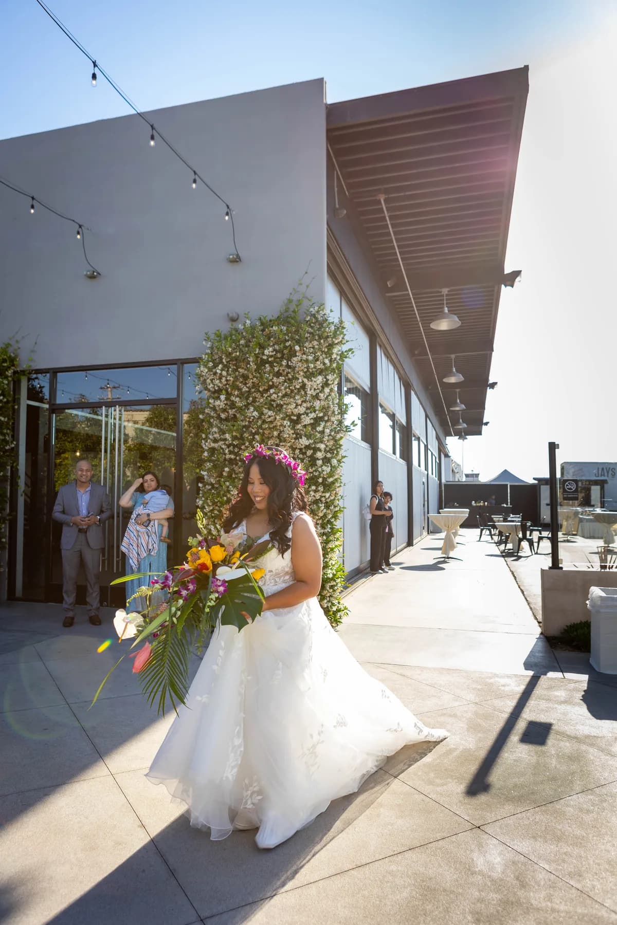 Azalea approaching the outdoor ceremony space in her wedding dress