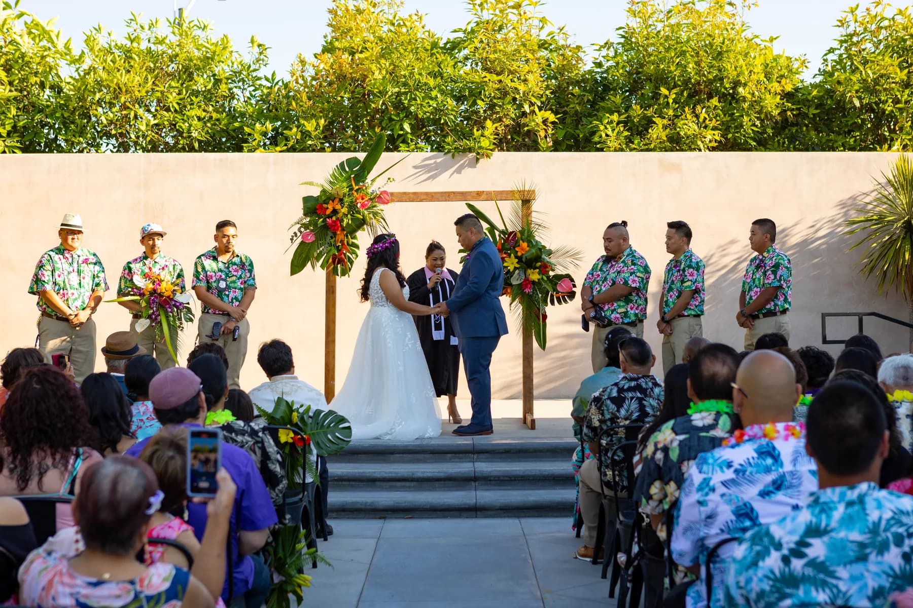 Wide view of Jed and Azalea beneath a tropical floral arch