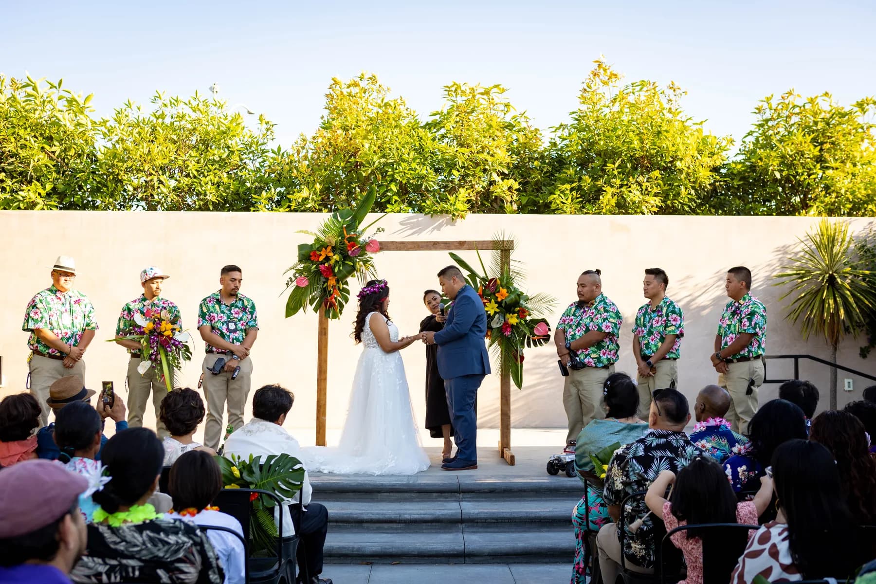 Jed and Azalea exchanging vows beneath the floral arch