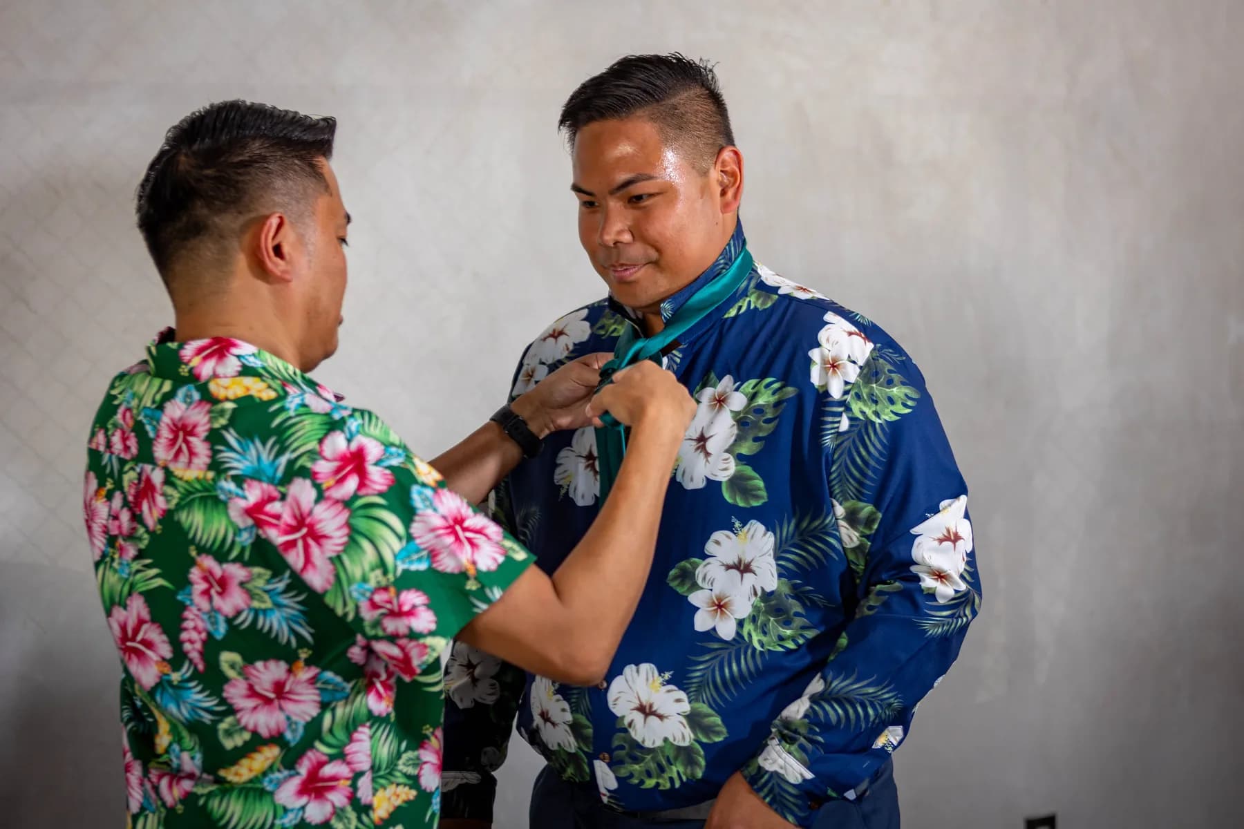 An attendant straightening Jed’s floral shirt before the wedding