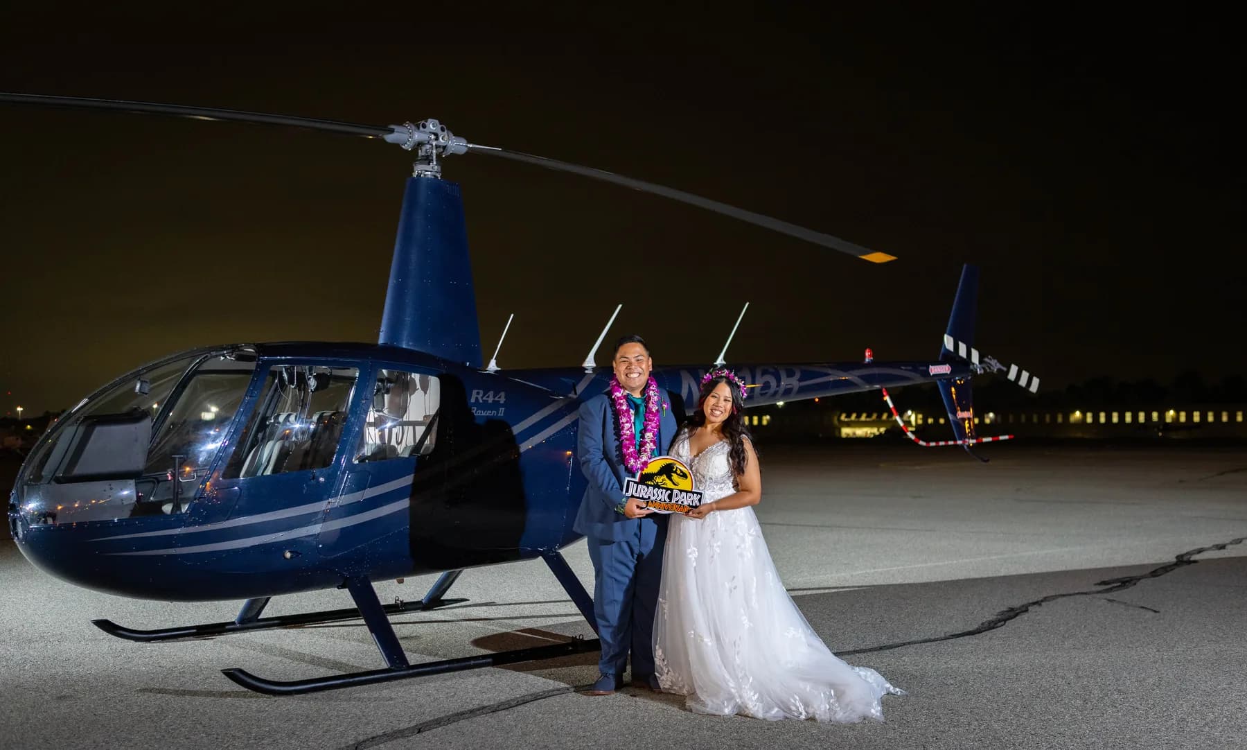 Jed and Azalea standing beside the blue helicopter at night