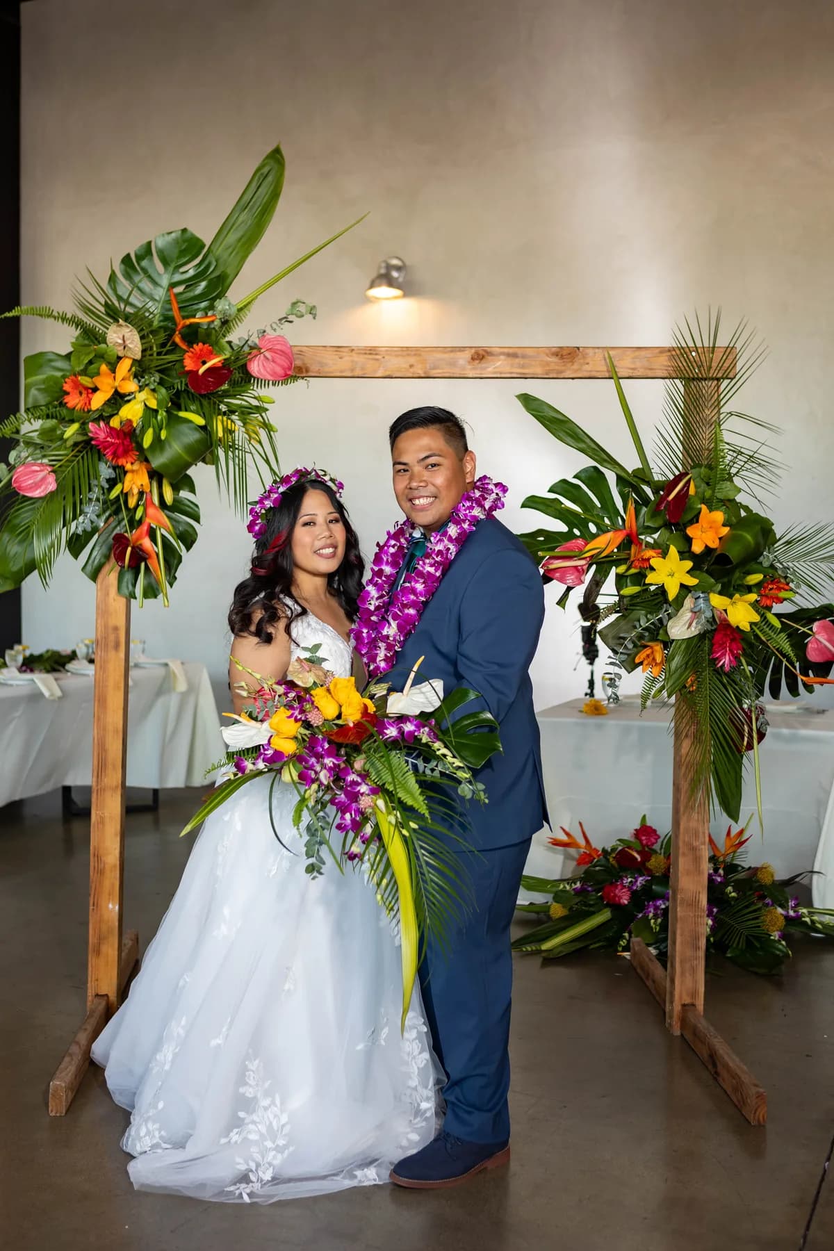 Jed and Azalea standing beneath a tropical floral arch