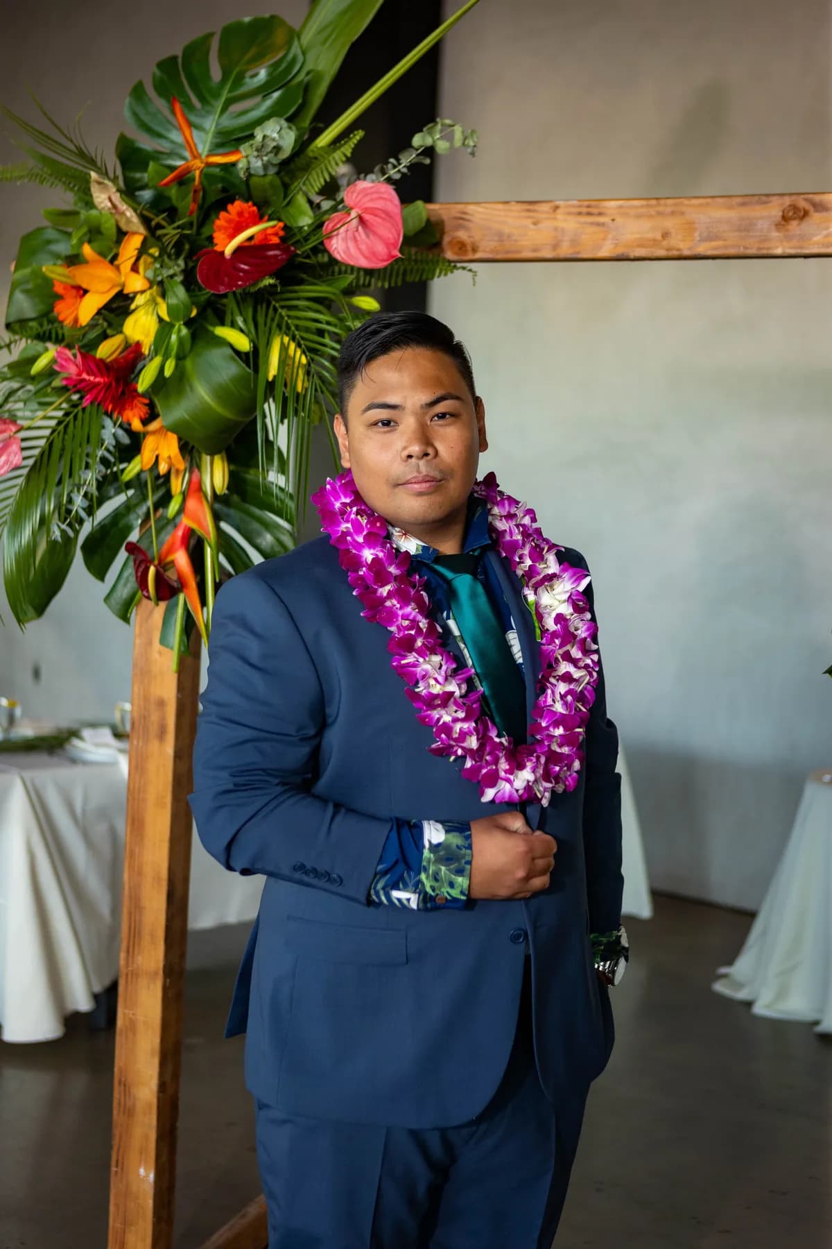 Jed standing alone beneath the floral ceremony arch
