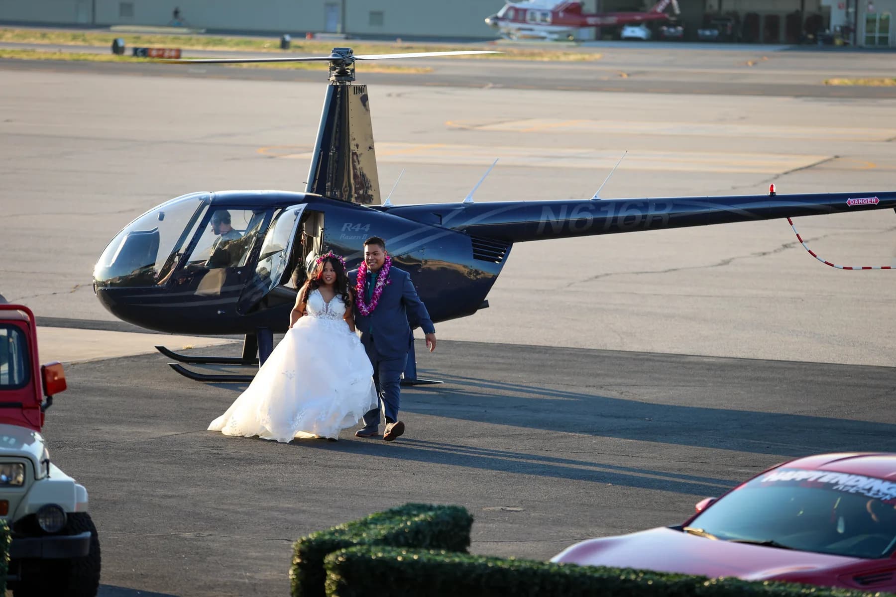 Jed and Azalea standing beside the blue helicopter in daylight