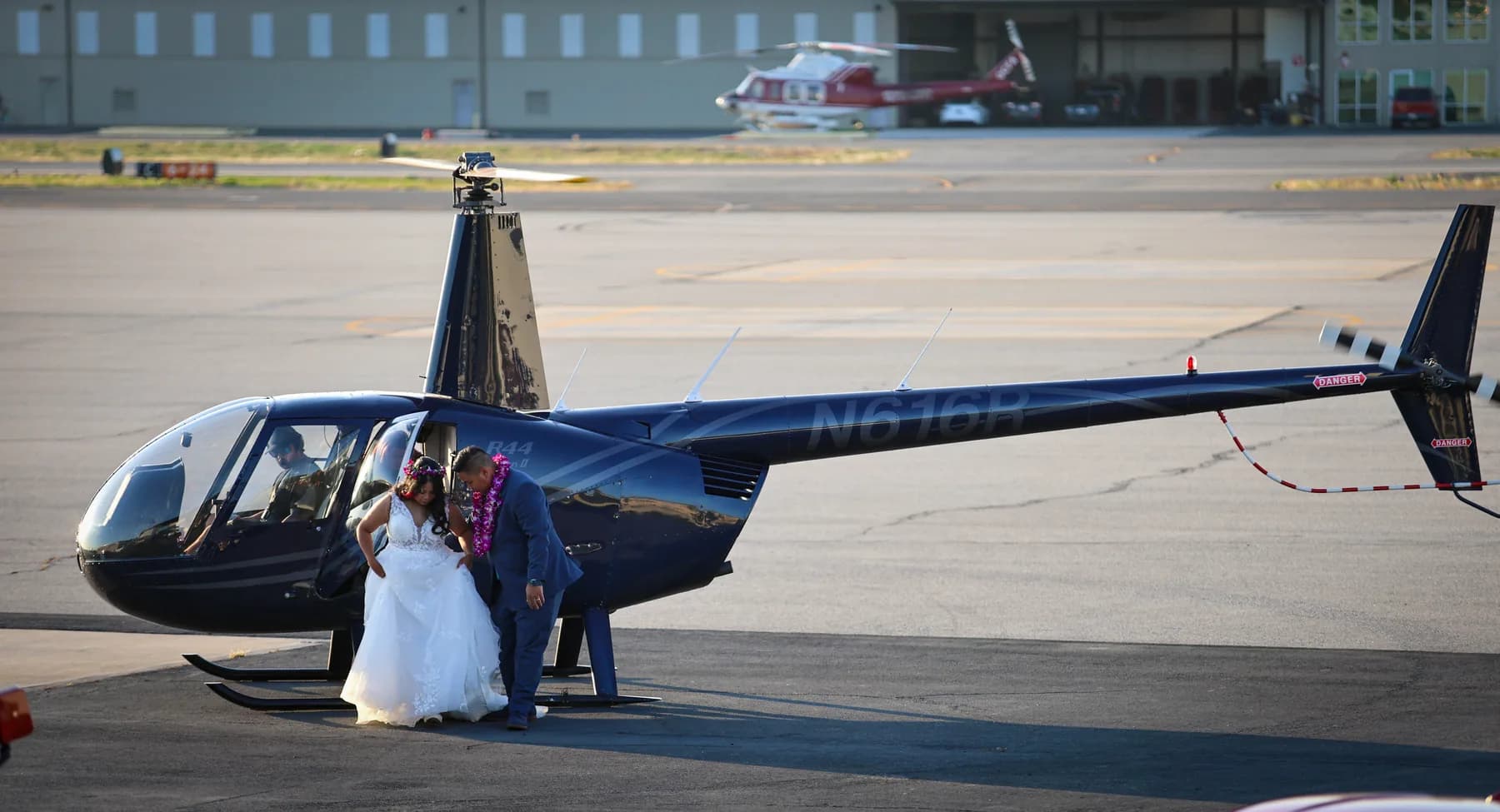 Jed helping Azalea step away from a blue helicopter at Fullerton Airport