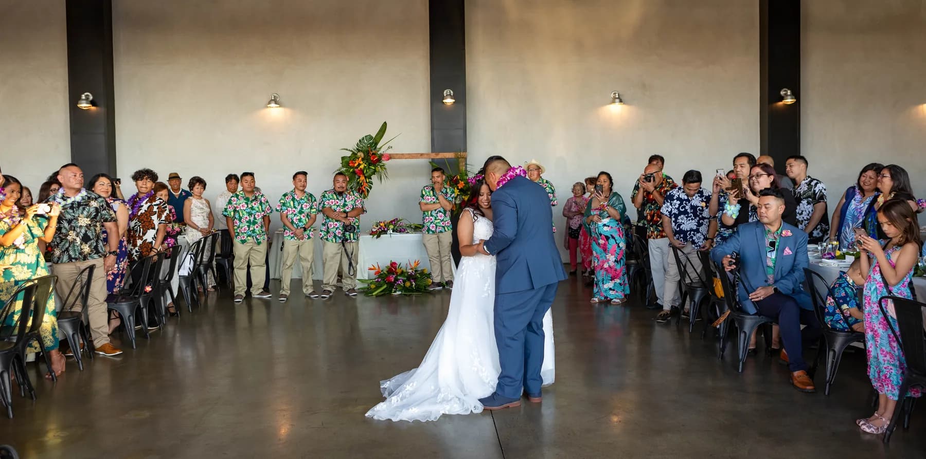 Jed and Azalea dancing as guests watch inside the hangar