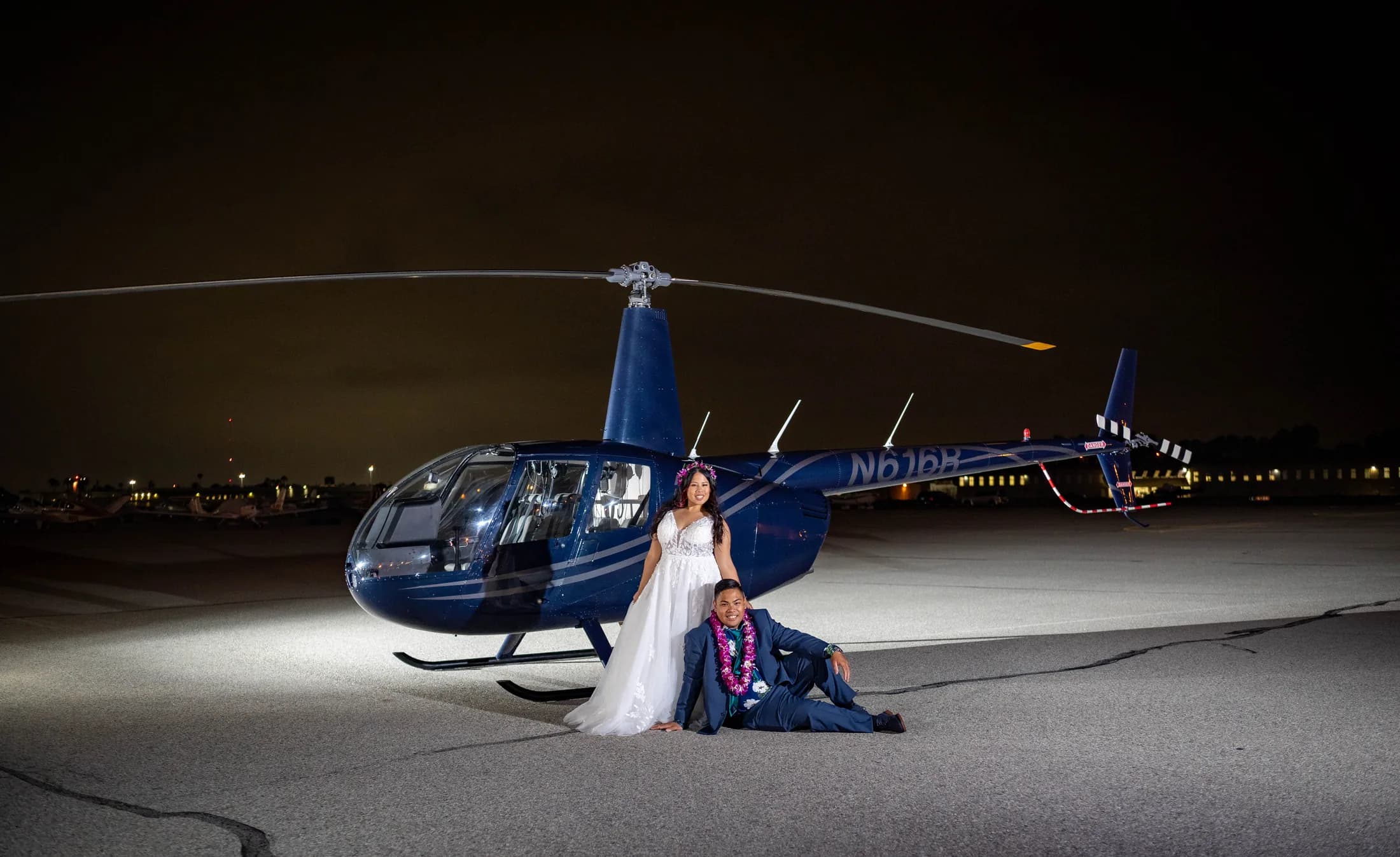 Jed and Azalea posed beside a blue helicopter on the Fullerton airfield at night
