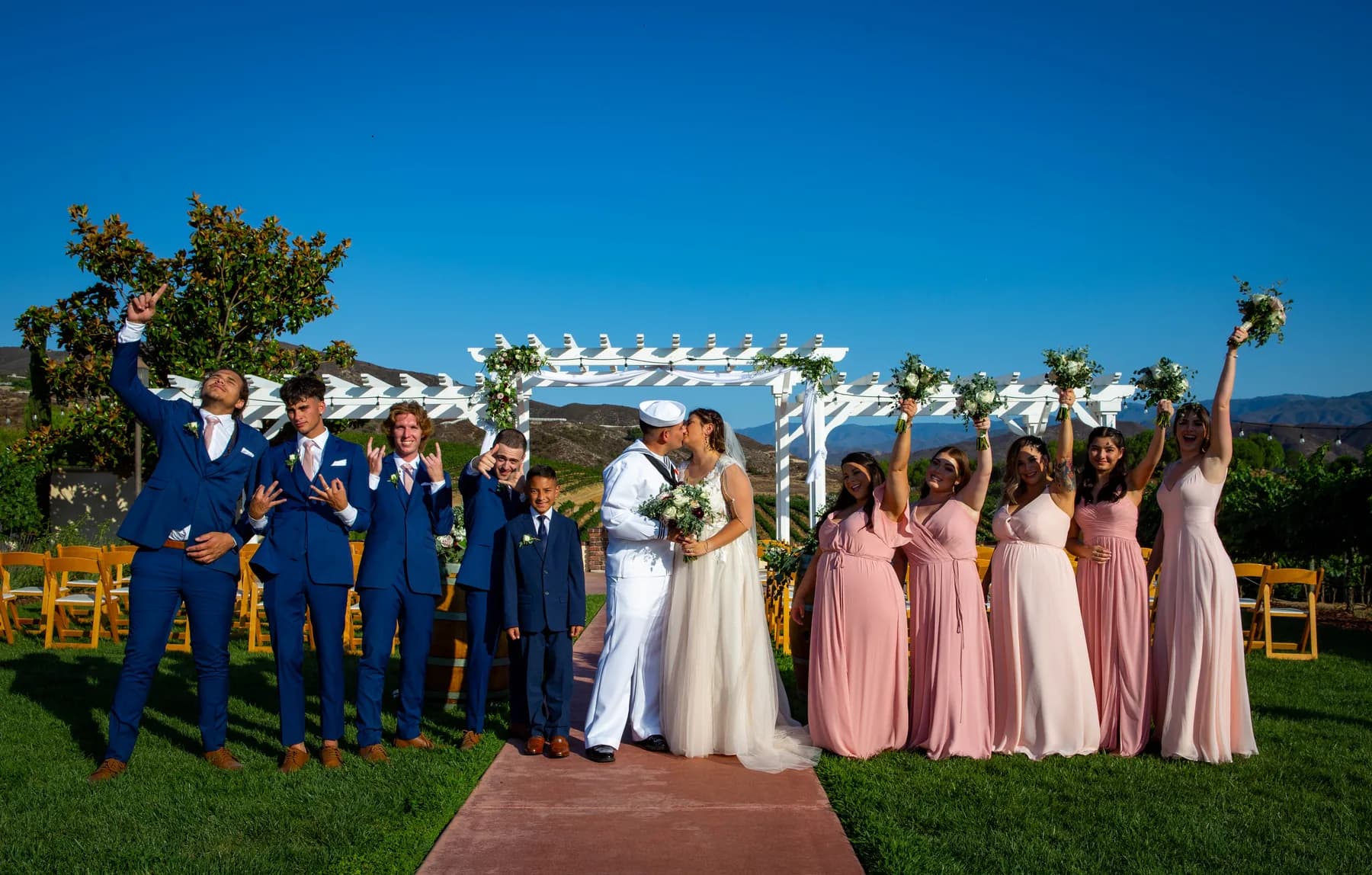Wedding party raising bouquets beside the vineyard