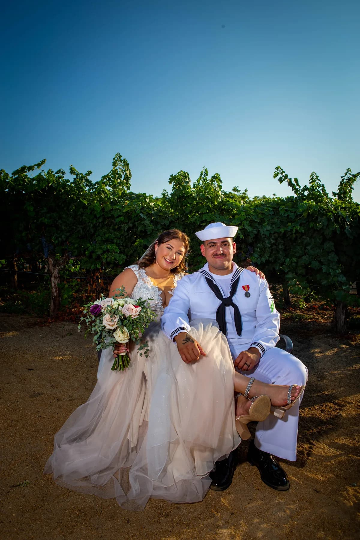 Deidriana and Gustavo seated together between vineyard rows