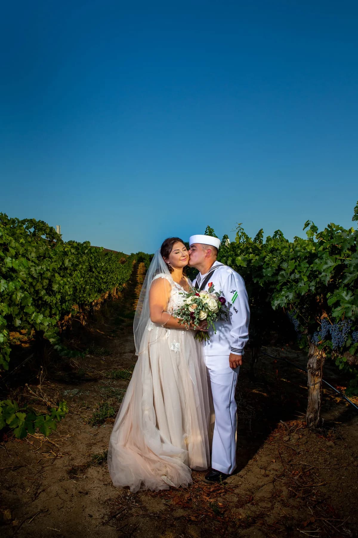 Deidriana and Gustavo standing closely among the vines