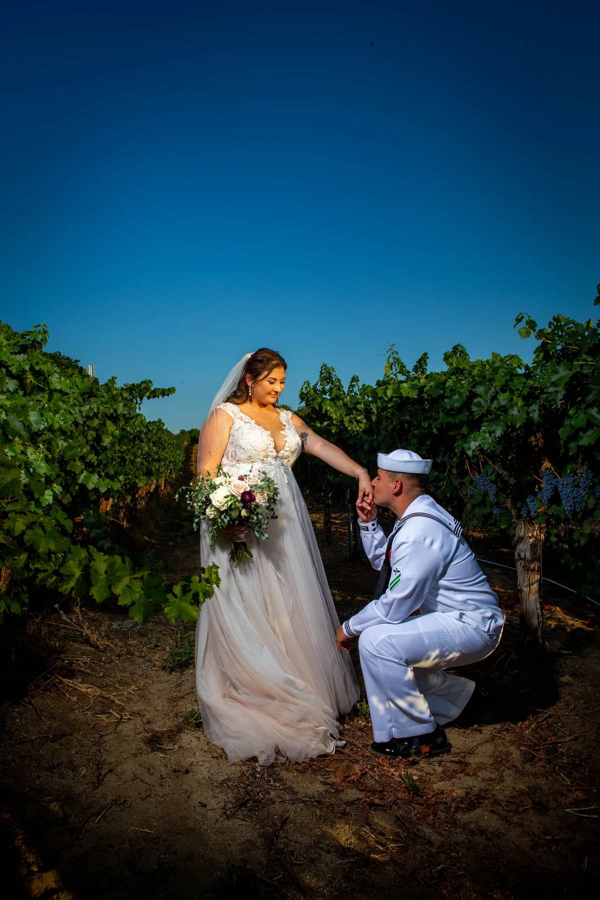 Gustavo kneeling beside Deidriana in the vineyard