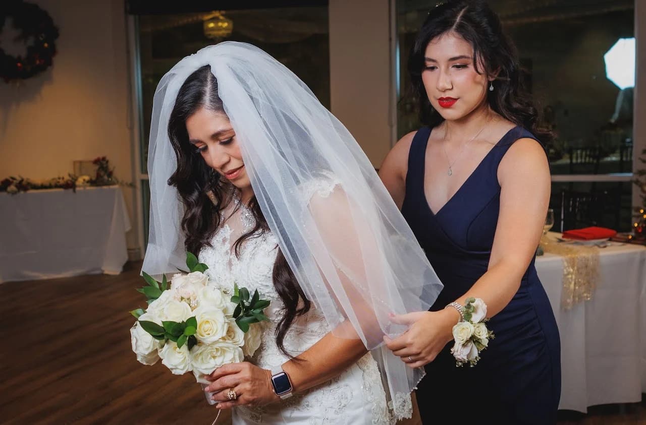 A woman helping arrange a gown and veil