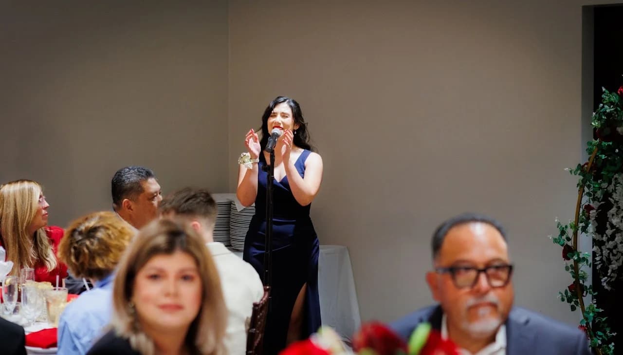 Woman speaking into a microphone among seated guests