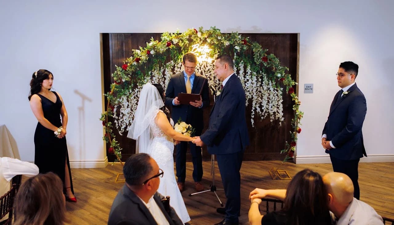 Couple and guests beneath a floral backdrop