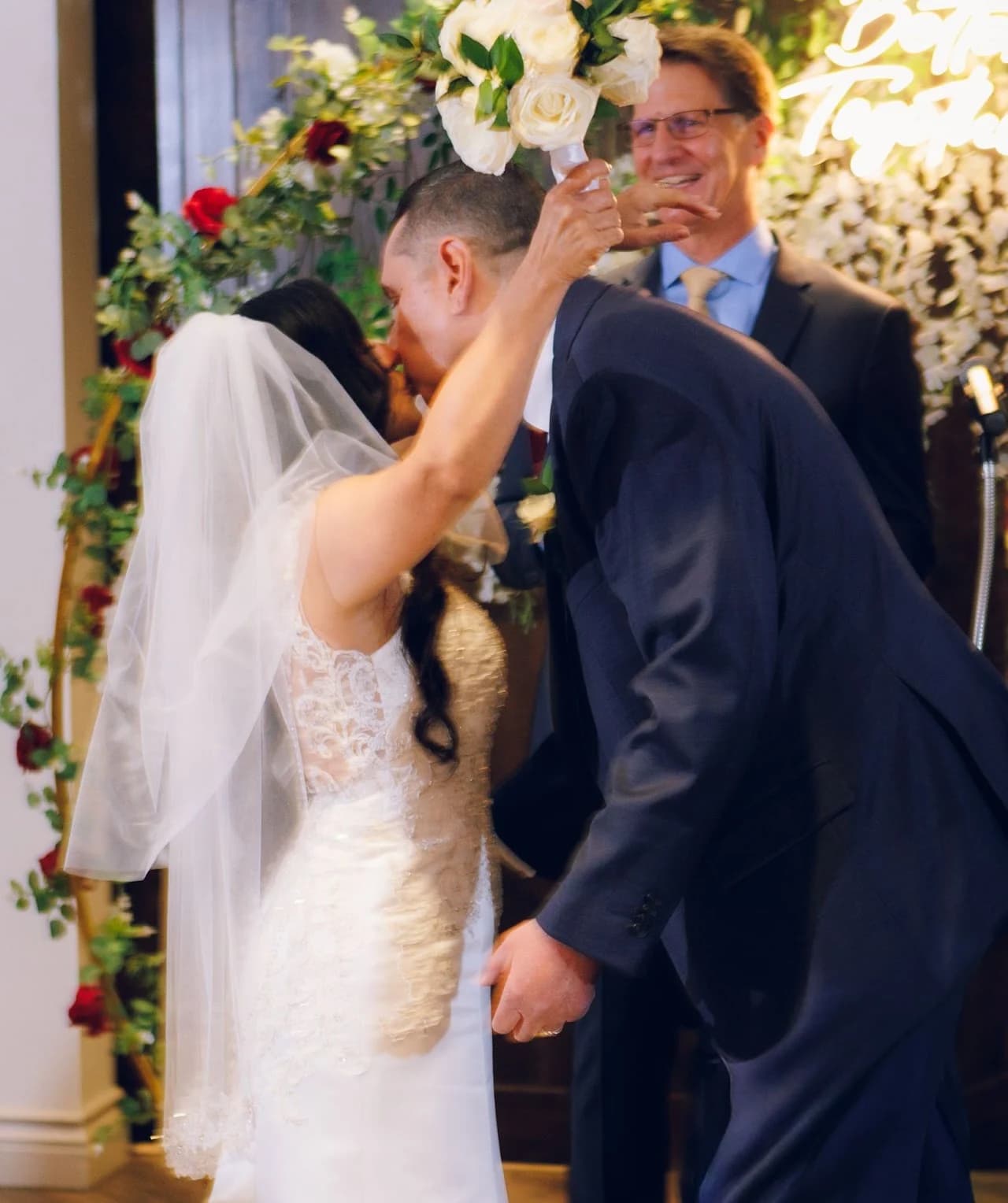 Couple kissing beside the floral backdrop