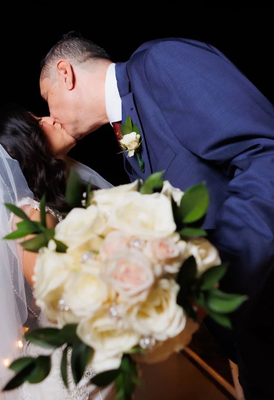 Close view of the couple kissing beside the bouquet