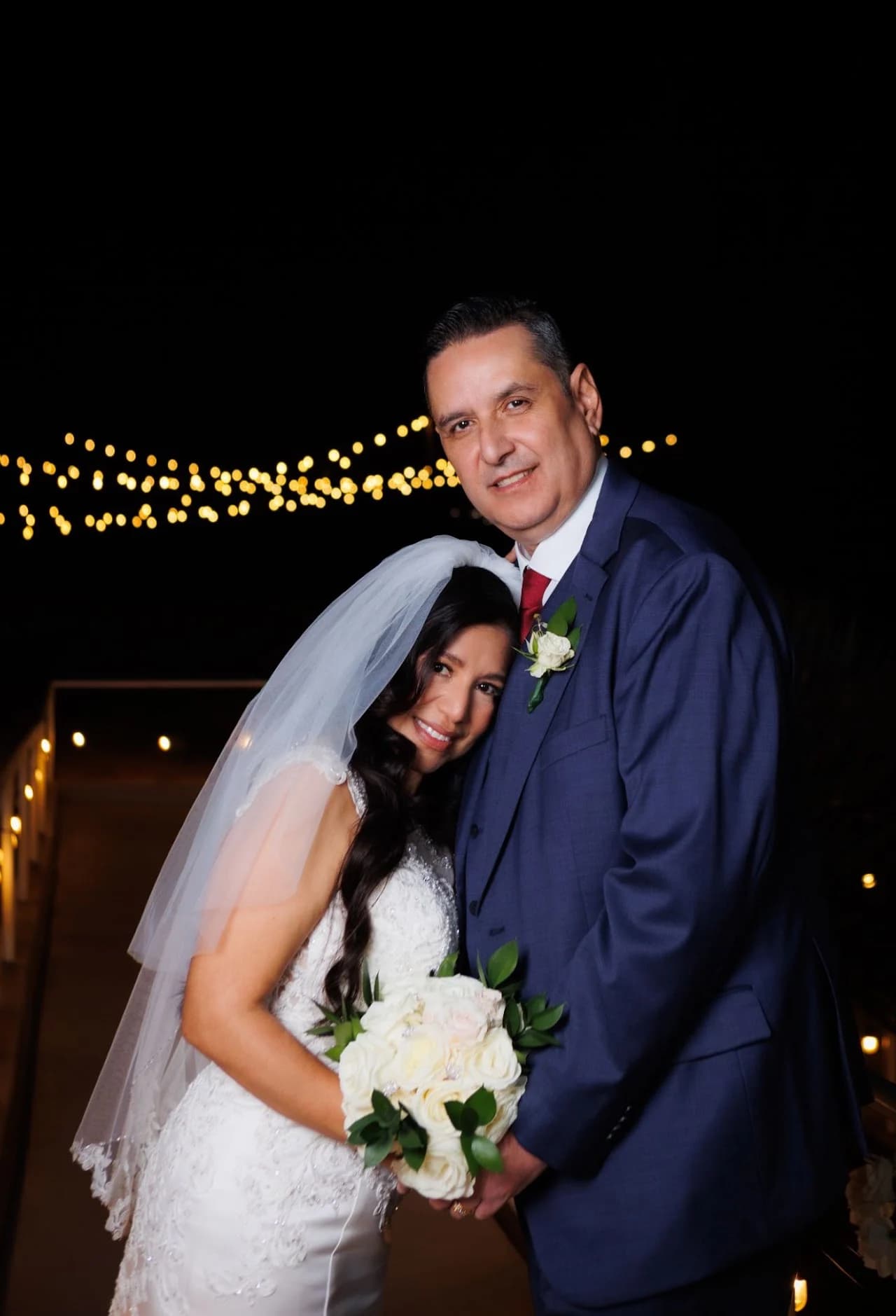 Couple embracing with string lights behind them