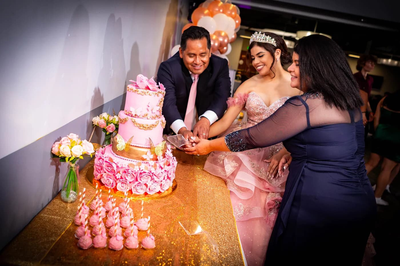 Quinceañera cutting a pink celebration cake with her family
