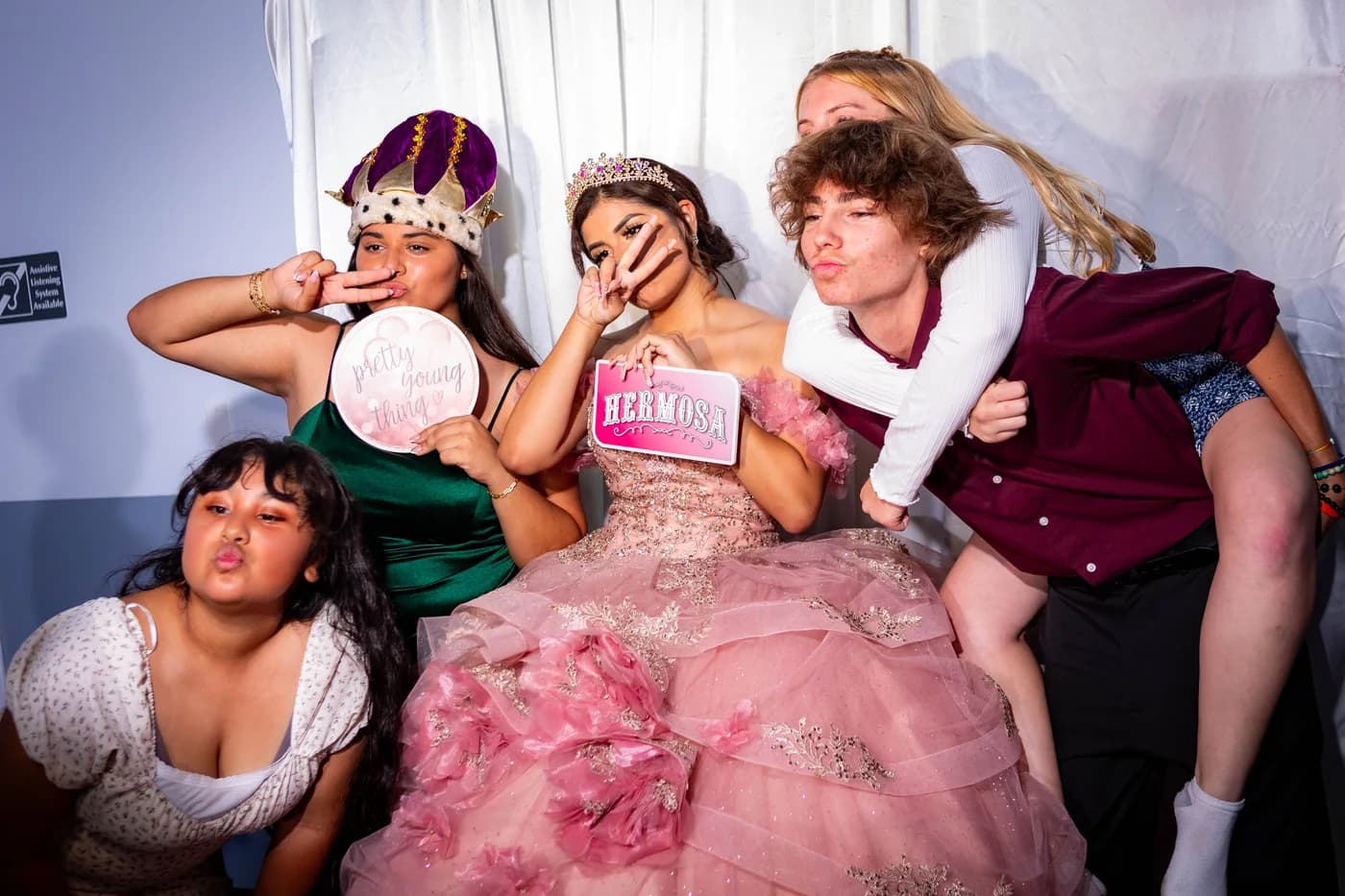 Quinceañera and friends posing together with playful photobooth props