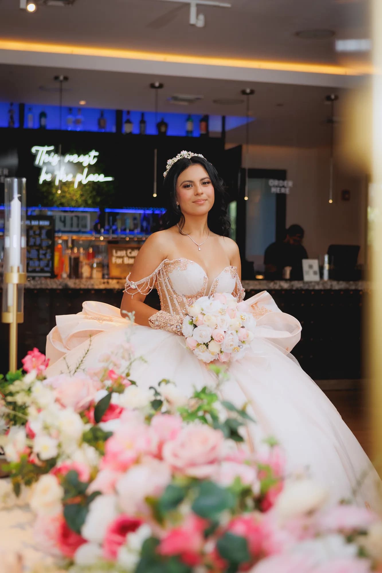 Isabella holding her bouquet behind pink reception flowers