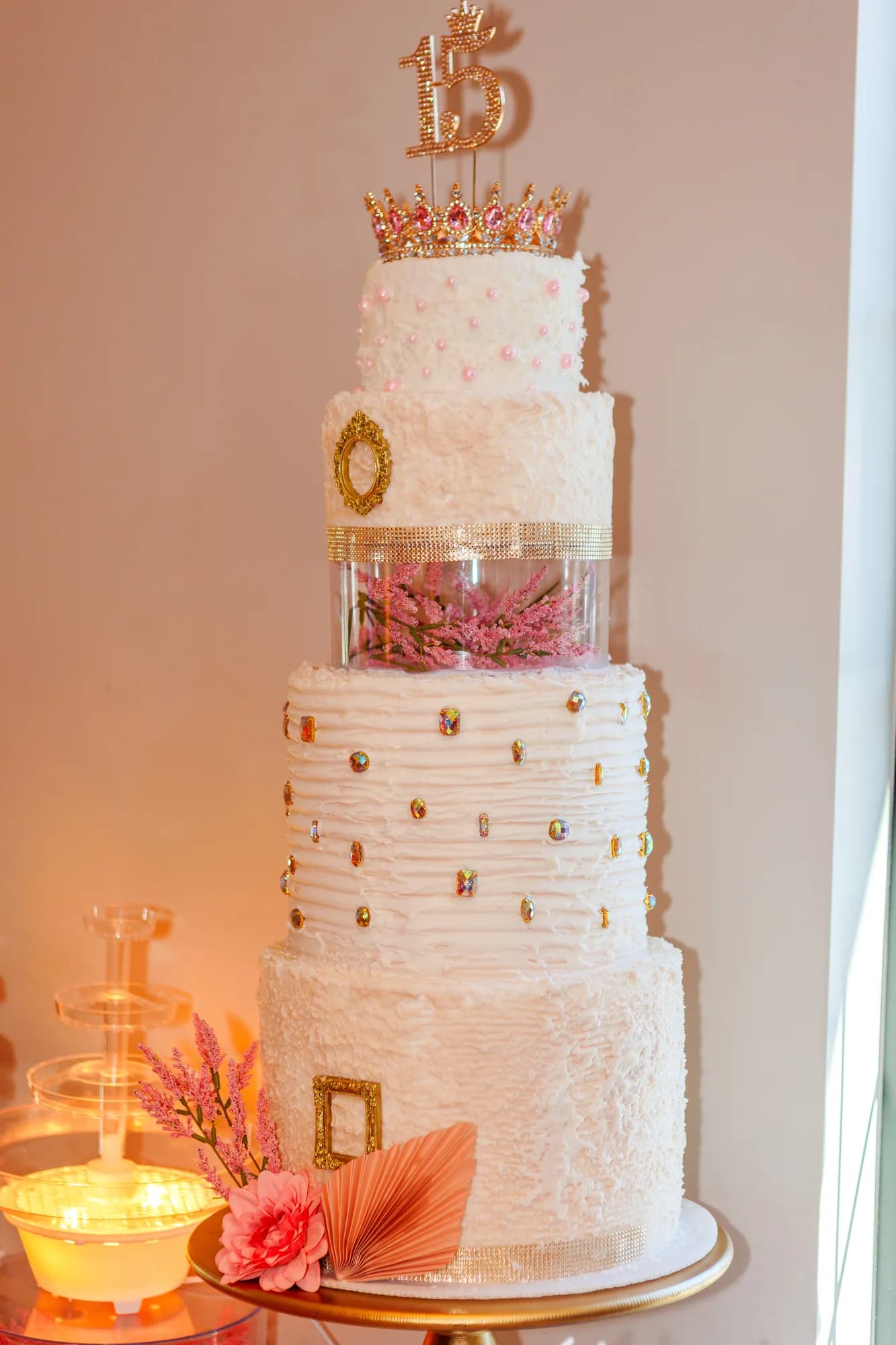 Tiered quinceañera cake topped with a gold fifteen