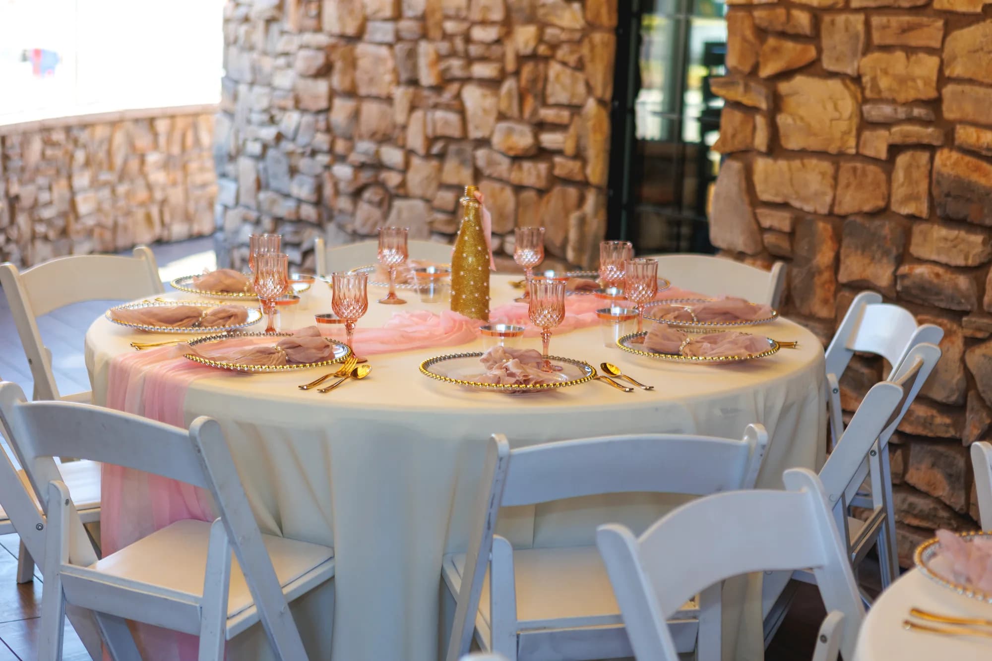 Pink table settings beside the loft’s stone wall