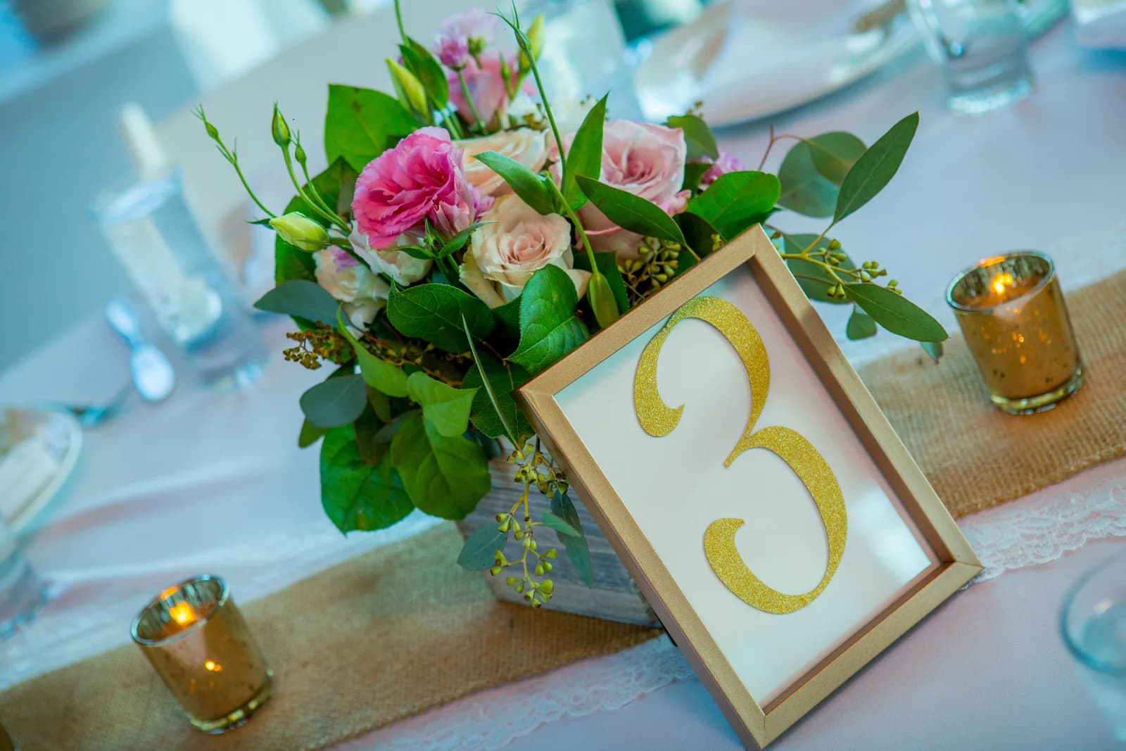 Pink wedding flowers and table number displayed at the reception