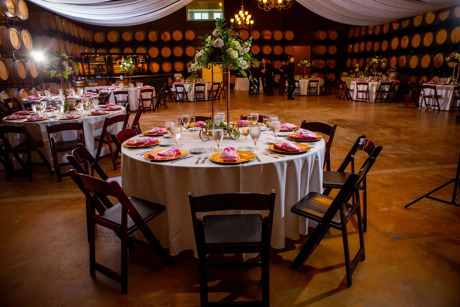 Reception tables surrounded by wine barrels and chandelier light