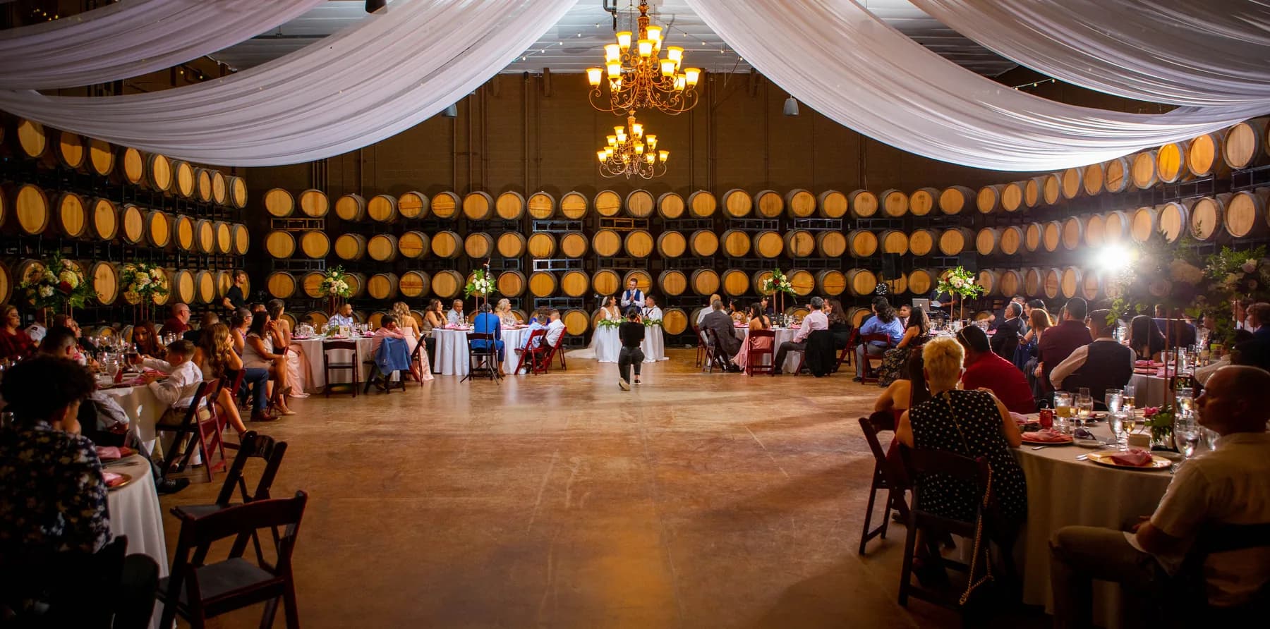 Wide view of the barrel-room reception with chandeliers and draped fabric