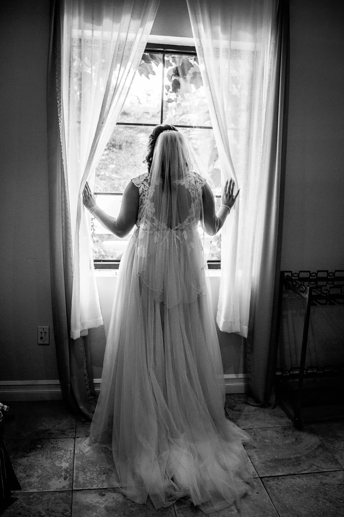 Black-and-white bridal portrait framed by a bright preparation-room window