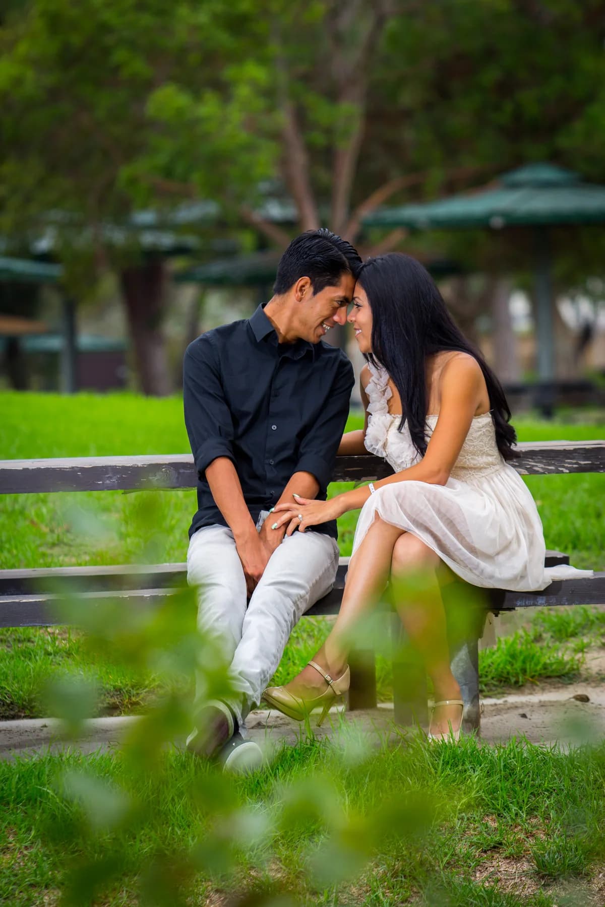 Couple smiling at each other while seated together on a wooden bench