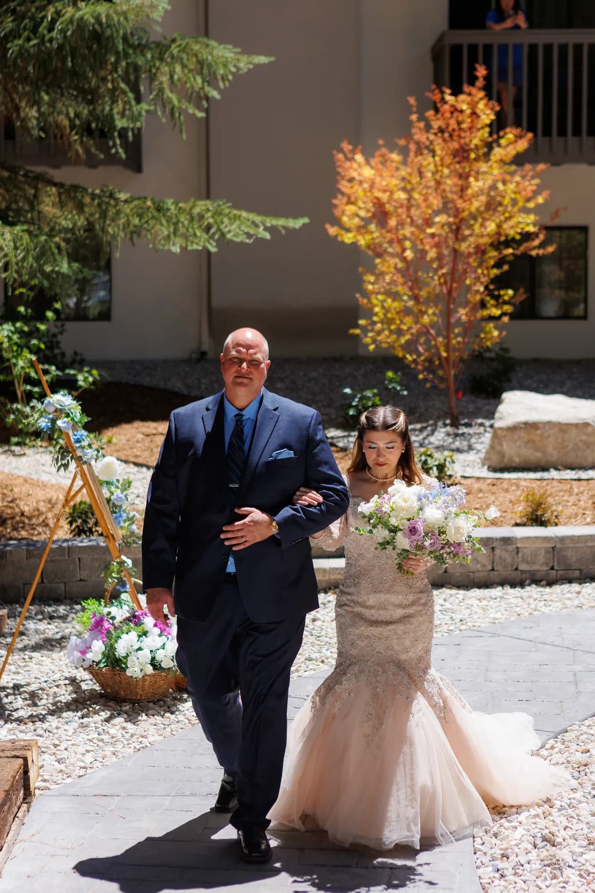 Gloria walking outdoors beside a companion with her bouquet