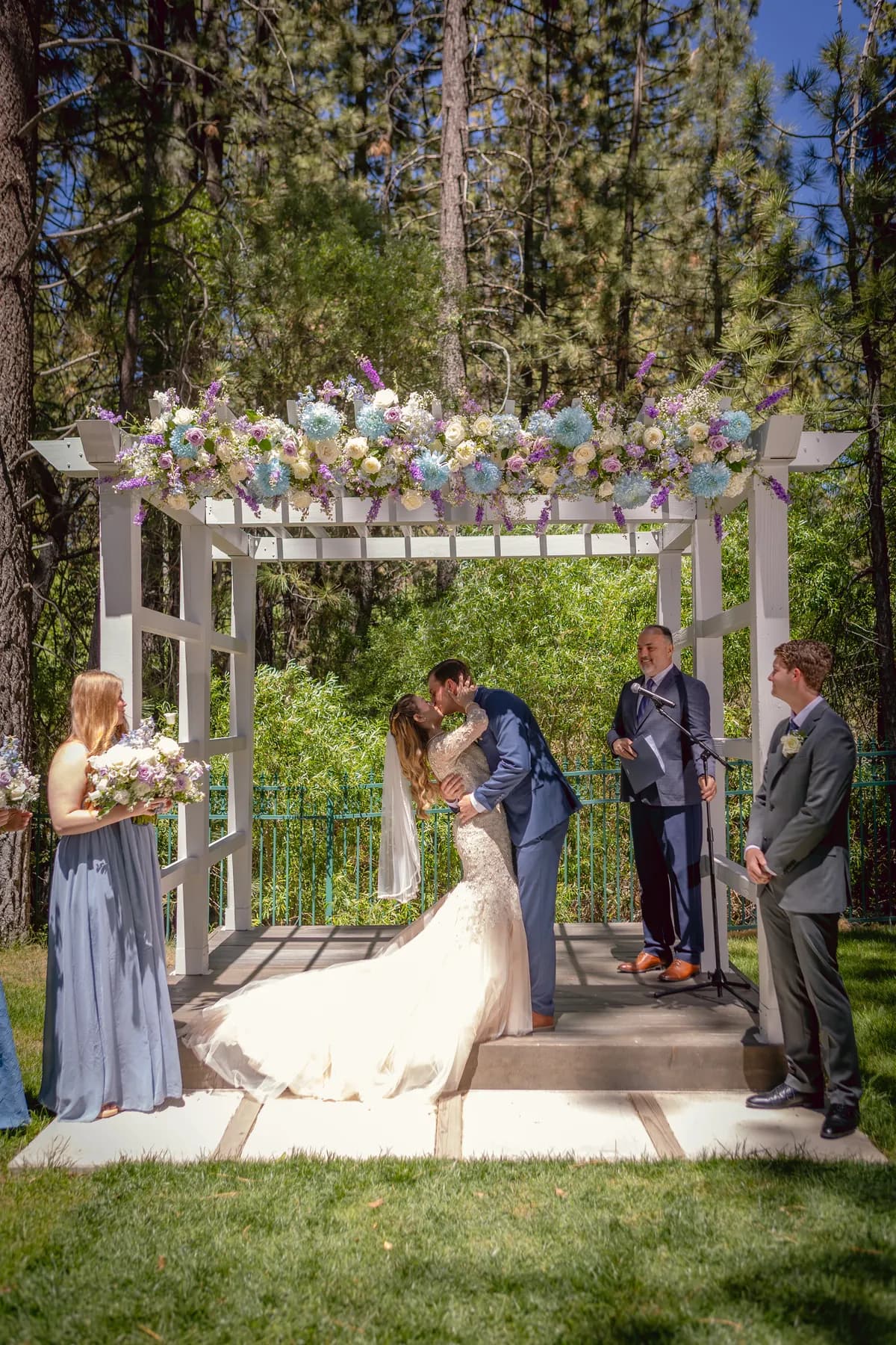 Gloria and Ryan kissing beneath the flower-covered ceremony arbor