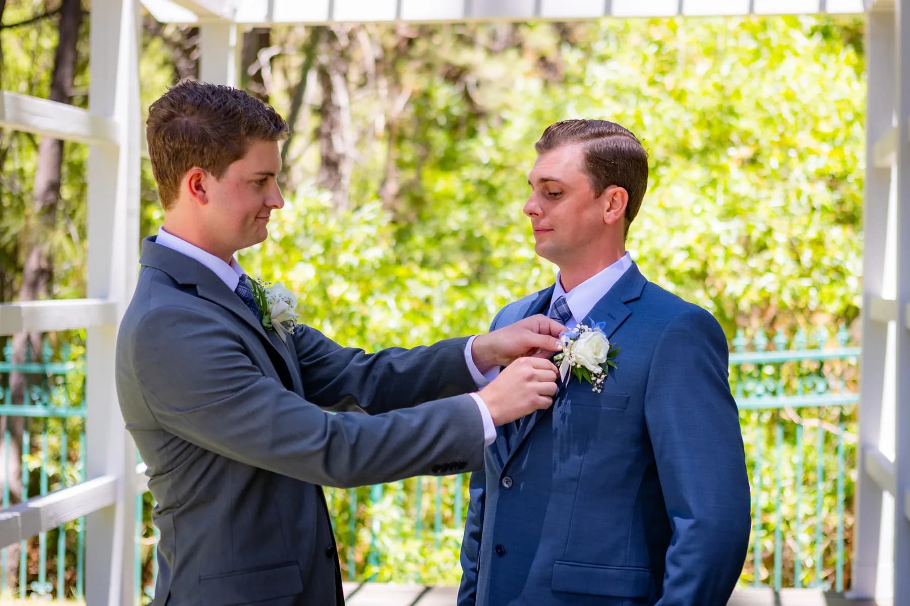 A companion straightening Ryan's boutonniere beneath the arbor