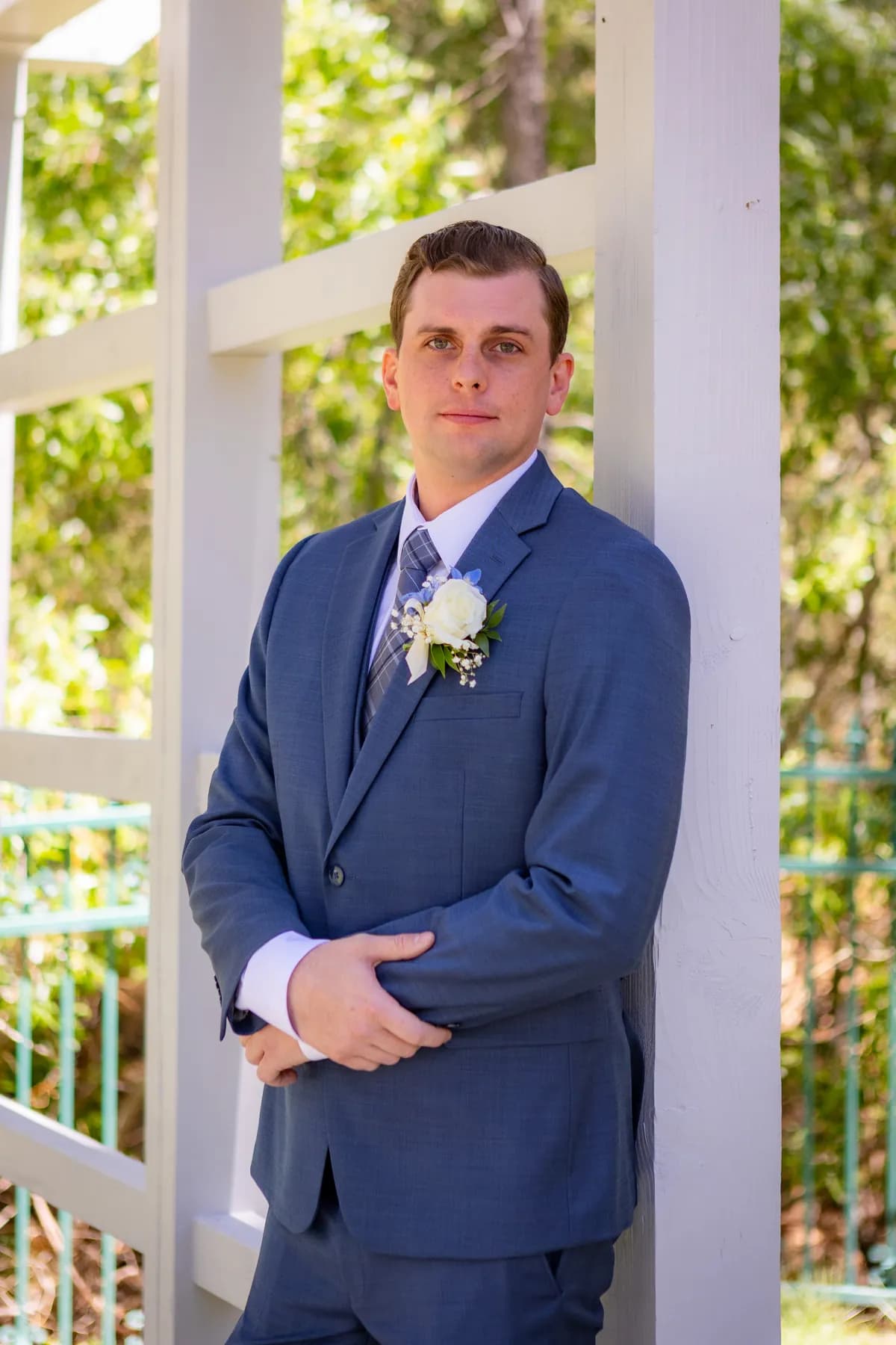 Ryan standing in a blue suit beside the outdoor arbor