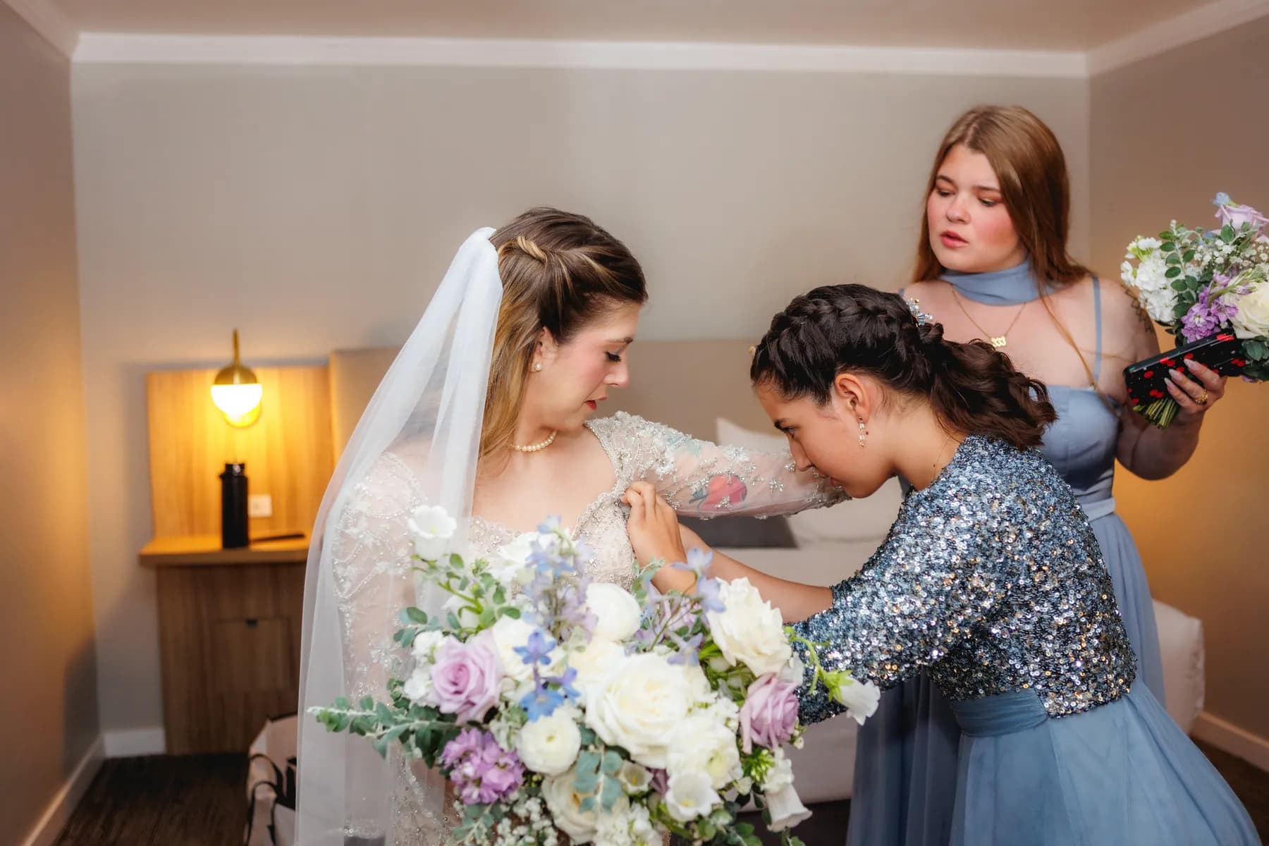 A companion adjusting Gloria's wedding dress as she holds her bouquet