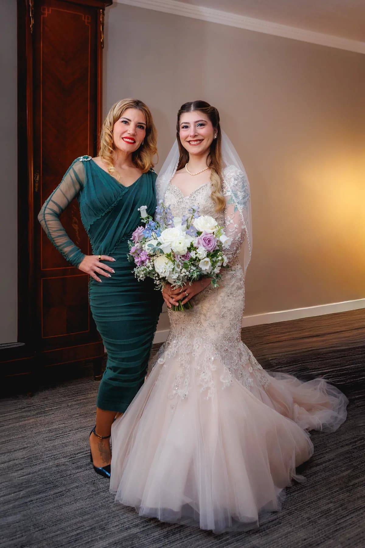 Gloria holding her bouquet beside a companion in a green dress