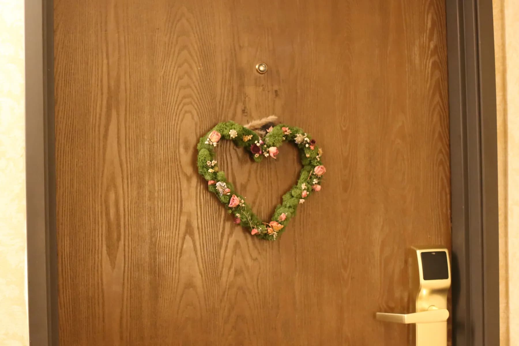 Heart-shaped floral wreath hanging on a wooden doorway