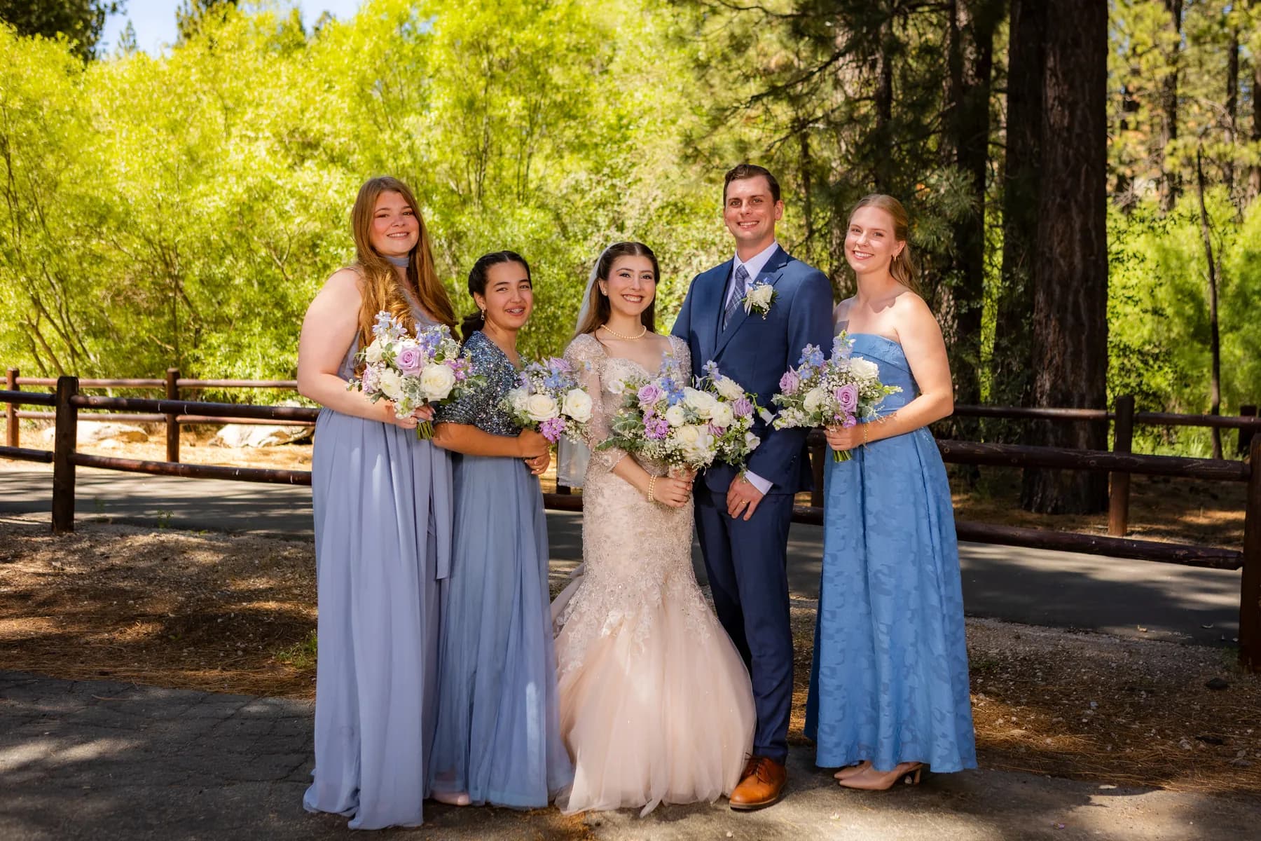 Gloria and Ryan standing with companions holding bouquets outdoors