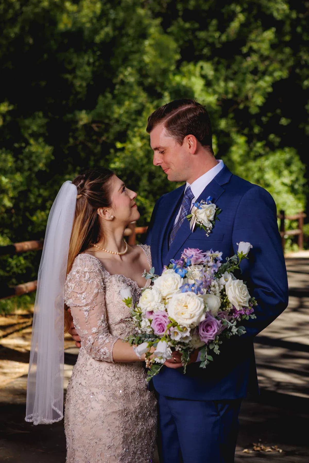Gloria and Ryan smiling together with a bouquet among pines