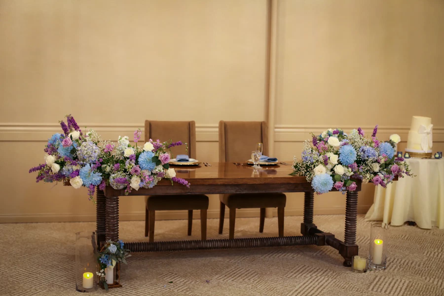 Floral arrangements on a reception table with the cake nearby
